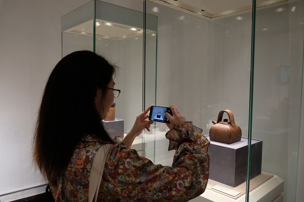 A visitor takes a photo of a square-shaped purple clay teapot at the Yucheng Kiln Cultural Research Institute in Ningbo, Zhejiang. /CFP