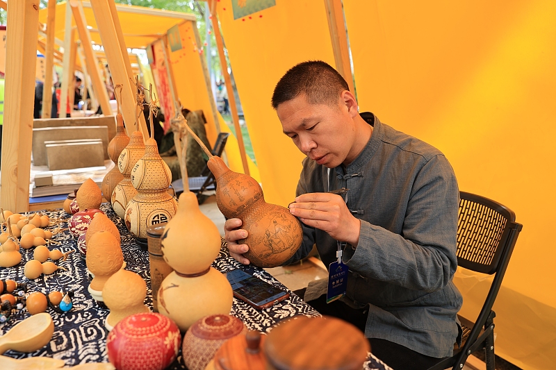 A craftsman carves patterns on a dry gourd at the Yellow River Fair in Dongying City, Shandong Province. /CFP