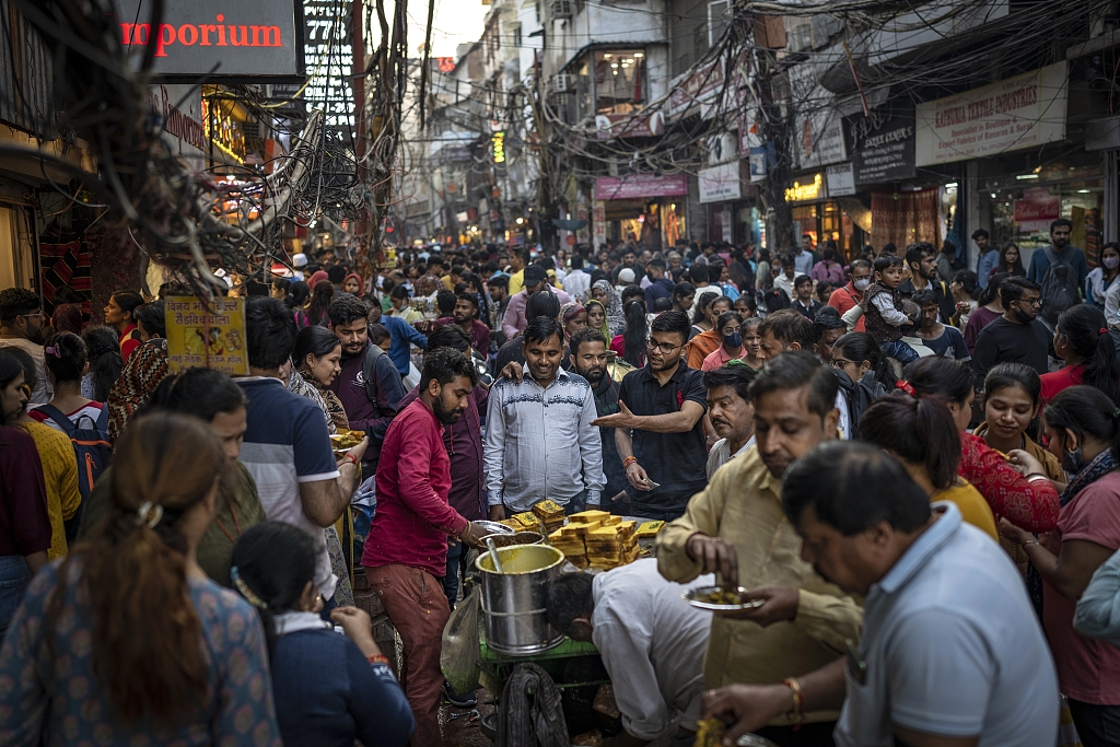 FILE - People eat street food as shoppers crowd a market in New Delhi, India, Nov. 12, 2022. /CFP