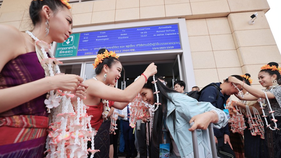 Lao staff members greet passengers taking the first cross-border passenger train from Kunming, capital of southwest China's Yunnan Province, to Lao capital Vientiane at the Boten Station of the China-Laos Railway in Luang Namtha, Laos, April 13, 2023. /Xinhua