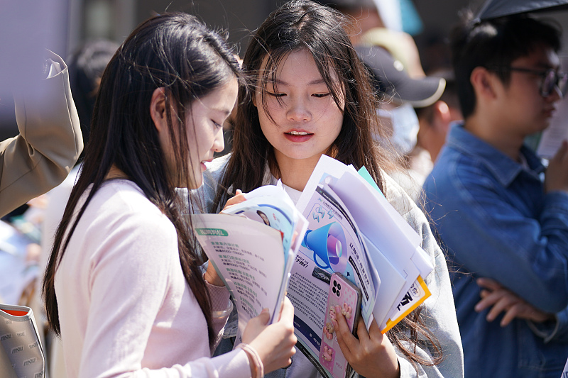 Students check company flyers at a job fair in Kunming, Yunnan Province, April 7, 2023. /CFP