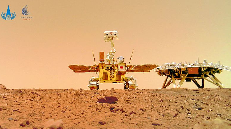 The image taken by a camera released from China's Zhurong Mars rover shows the rover (L) and the landing platform on the surface of Mars, June 11, 2021. /China National Space Administration via CFP