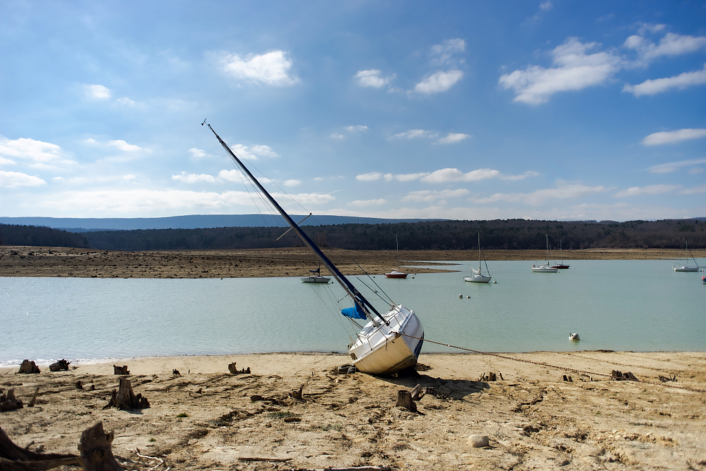 A grounded sailing boat on the exposed lakebed at the dried out Montbel Reservoir in Leran, France, March 1, 2023. /CFP
