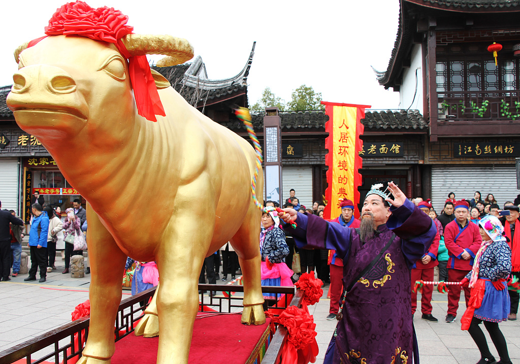 A man wearing traditional outfits whips a model of a 