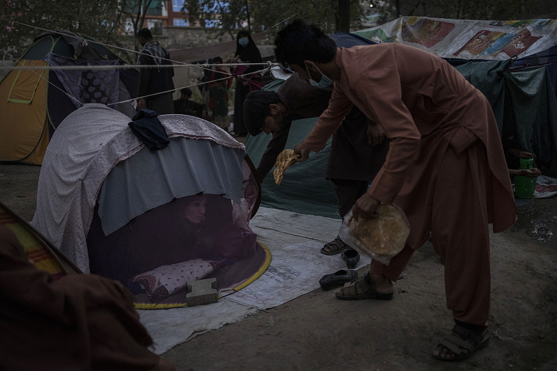An Afghan distributes food donations to a displaced person, Kabul, Afghanistan, September. 13, 2021. /CFP