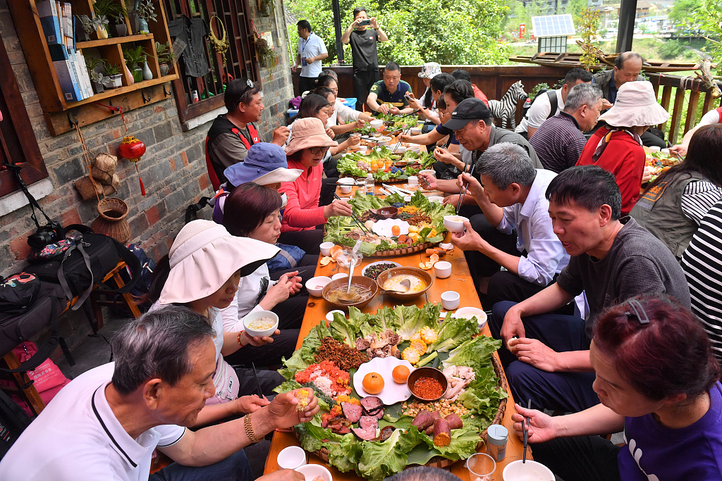 People tuck into traditional Miao snacks and dishes to celebrate the Miao Sisters Festival in Taijiang County of southwest China's Guizhou Province on May 4, 2023. /CFP