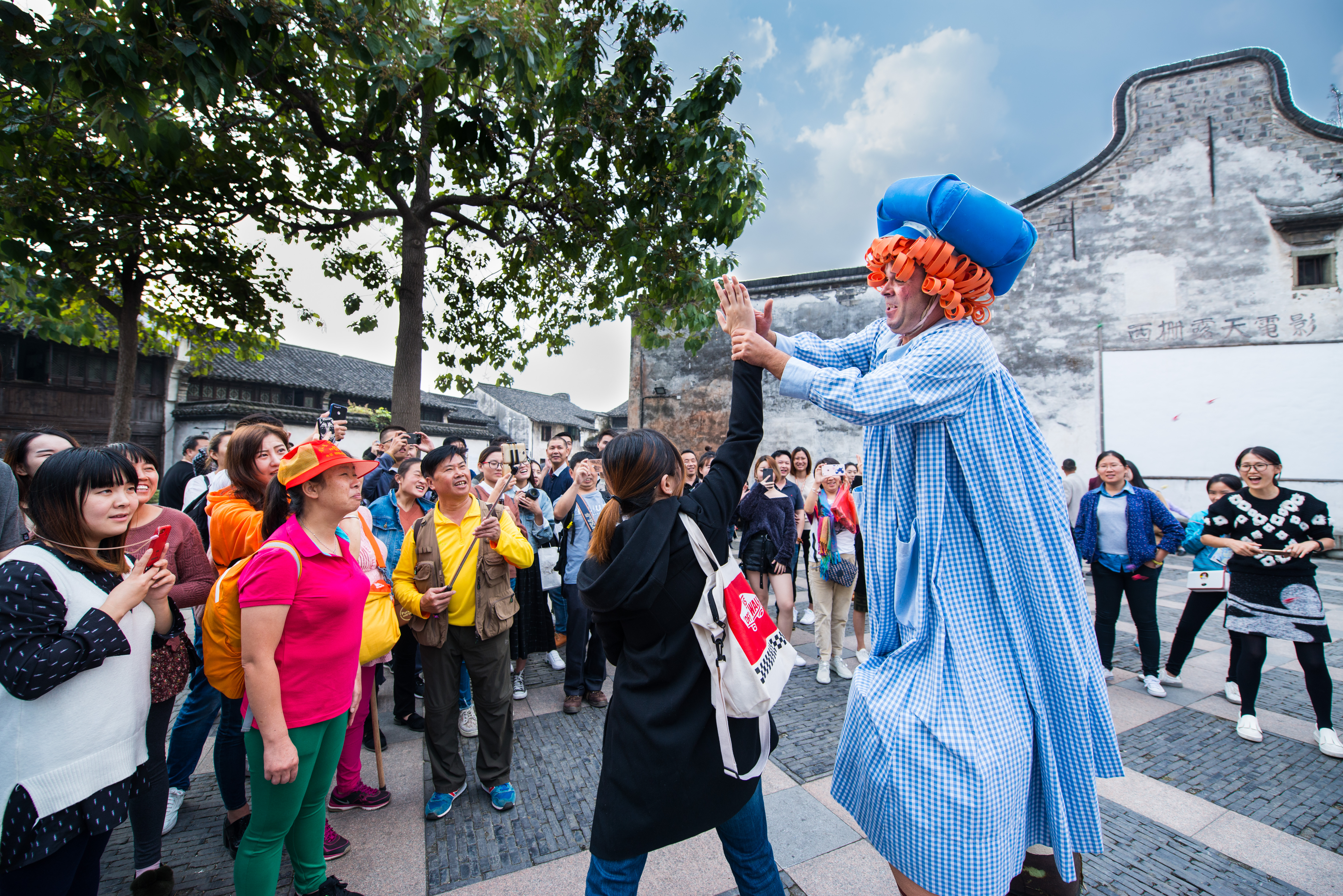 The file photo shows a stilt performer interacting with the audience at an outdoor carnival during the Wuzhen Theatre Festival. /Photo provided to CGTN