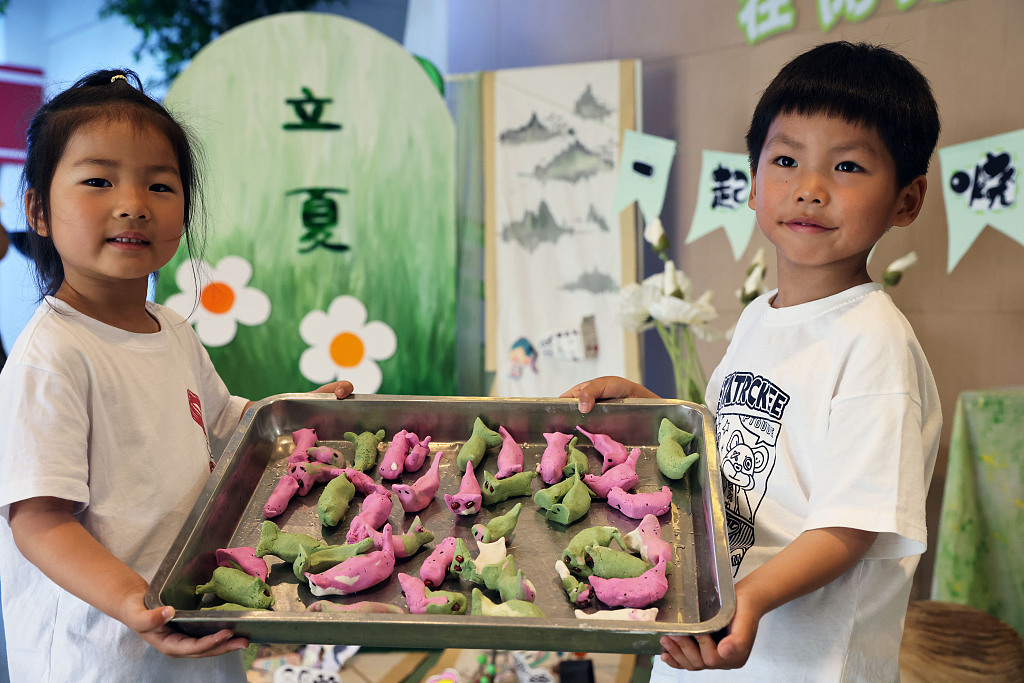 Kindergarten kids in Huzhou, Zhejiang show off dog-shaped sticky rice buns they made with the help of teachers on May 5, 2023. /CFP