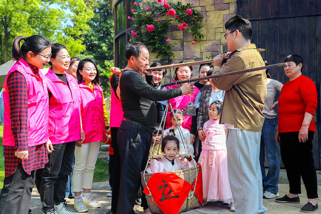 A file photo shows locals in Huzhou, Zhejiang Province keeping up the tradition of weighing children during the Lixia solar term using an ancient method. This tradition is fun for the kids and reassures their parents that they are in good health for the coming summer. /CFP