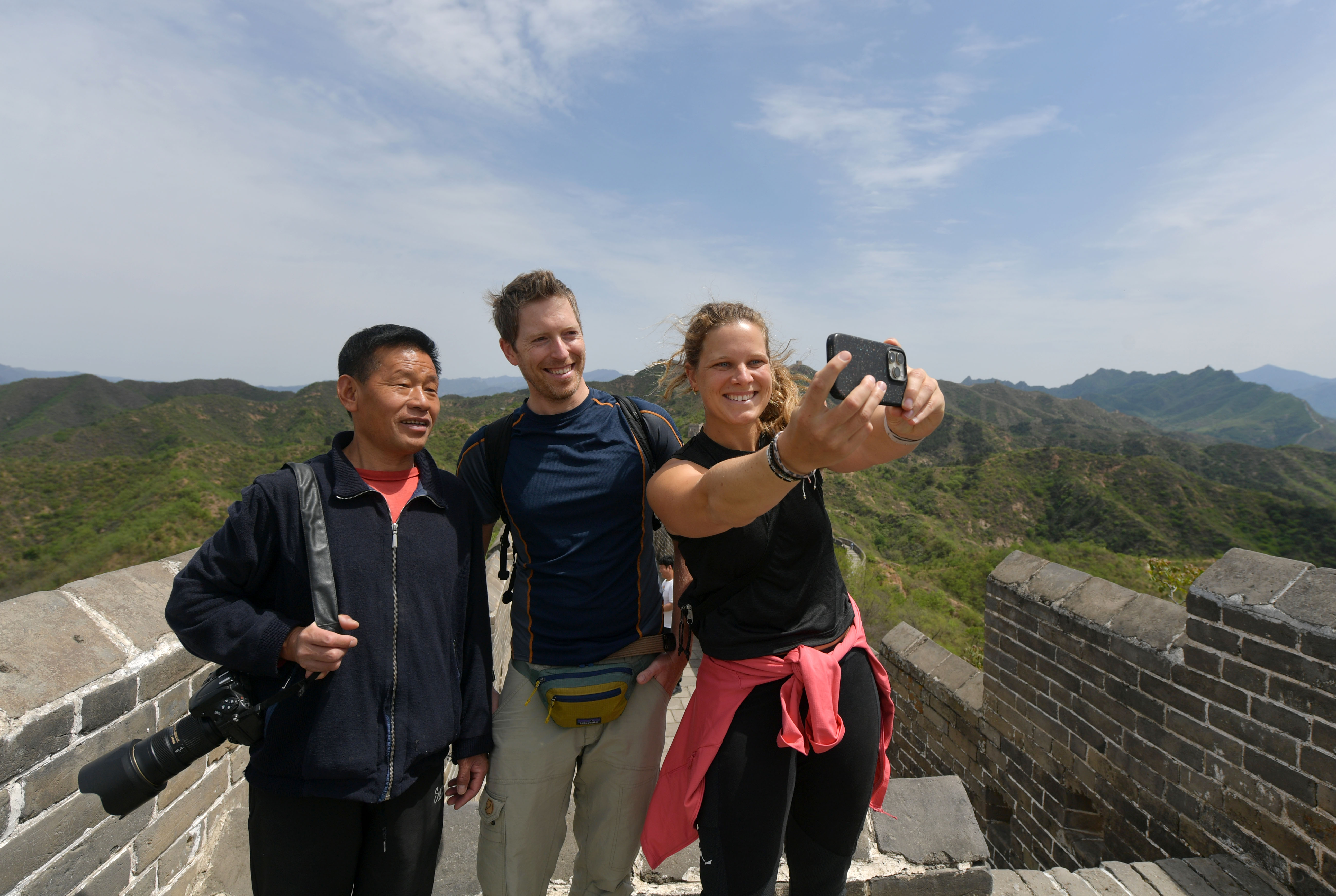 Zhou Wanping (left) takes photos with visitors to the Great Wall. /CNSPHOTO