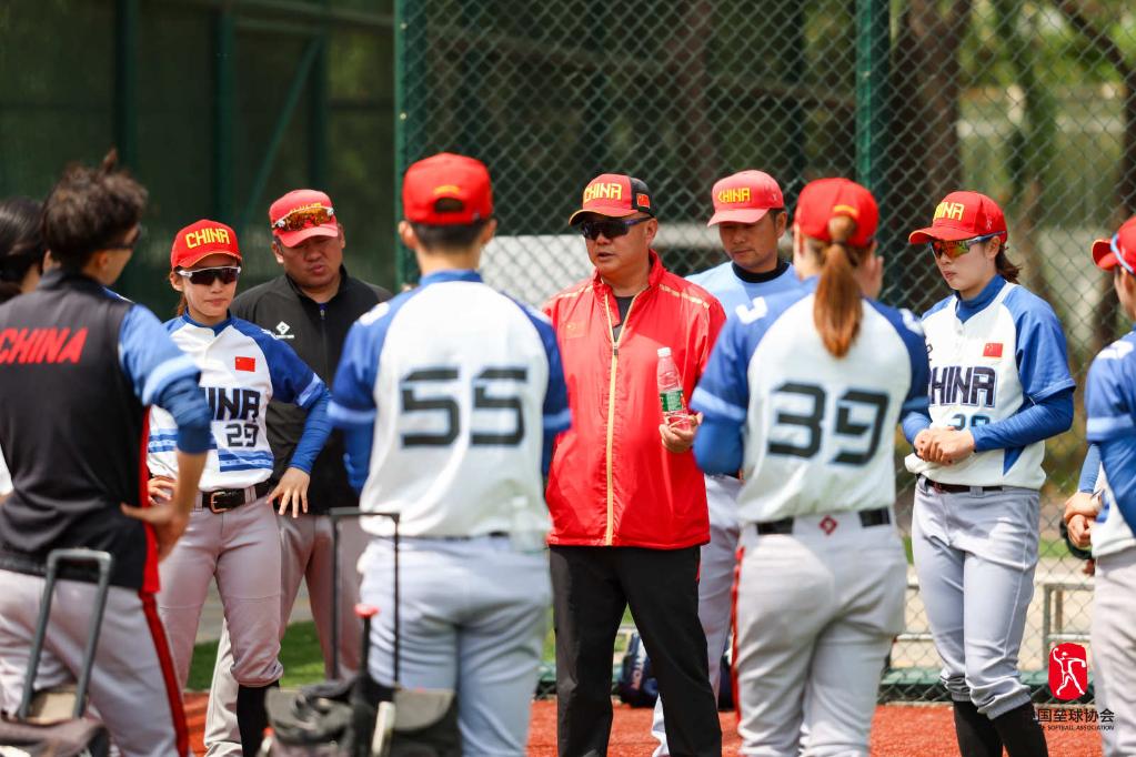 Tang Changdong (C), head coach of the Chinese women's national softball team, talks to his players during practice. /Chinese Softball Association