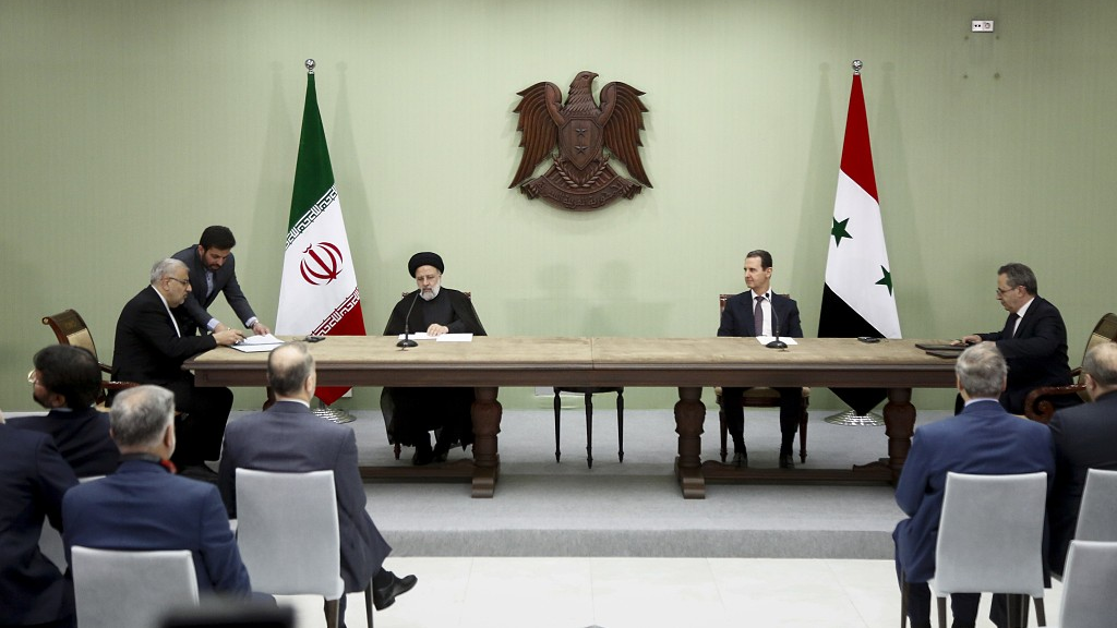 Syrian President Bashar al-Assad (R) and Iranian counterpart Ebrahim Raisi exchange documents after signing a memoranda of understanding on 