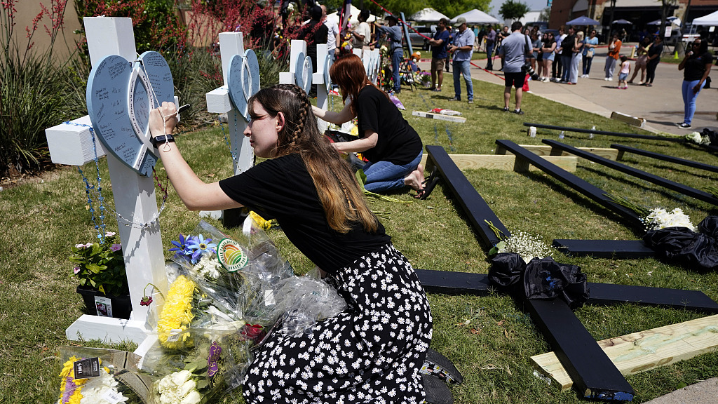 Jennifer Seeley signs a cross at a makeshift memorial by the mall where the deadly shooting happened in Allen, Texas, U.S., May 8, 2023. /CFP