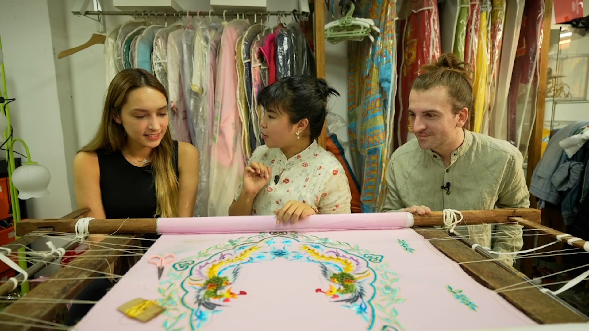 Minh Hoa Piron (left) from the United States and Jacopo Maria Lasala (right) from Italy talk with He Fengting at the Zhuangyuanfang Costume Factory in Guangzhou, south China's Guangdong Province. /CMG
