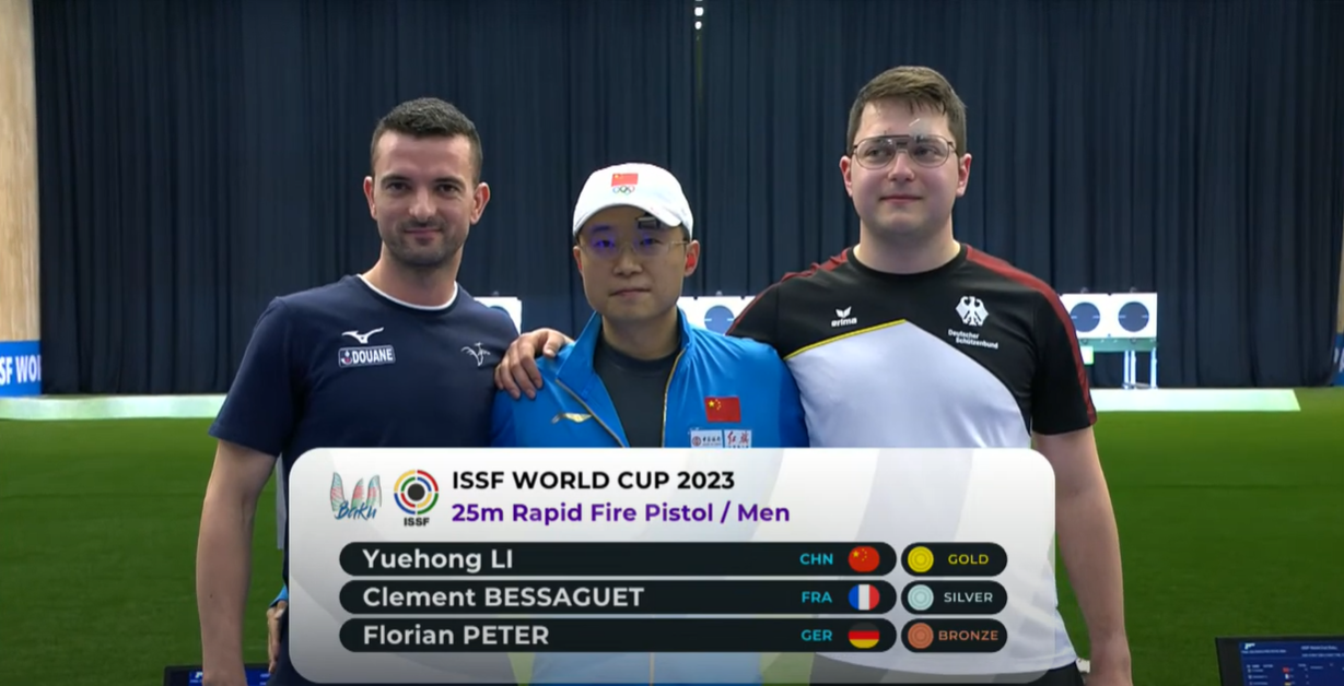 A screenshot of players Li Yuehong (C) of China, Clement Bessaguet (L) of France and Florian Peter of Germany, showing the medal table after the men's 25-meter rapid fire pistol final. /ISSF