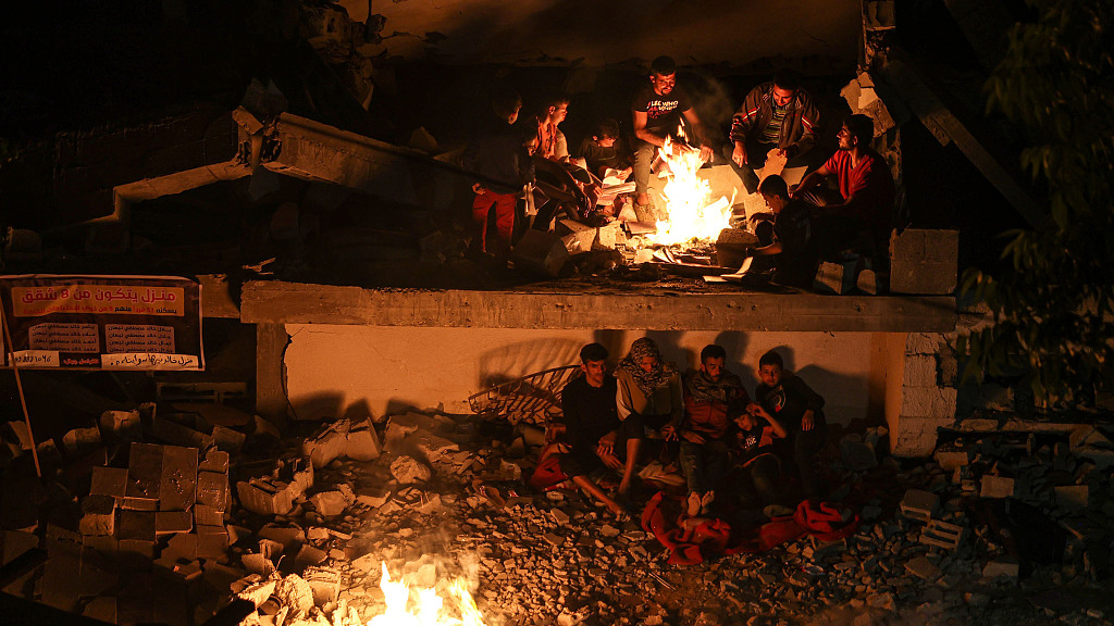 Palestinian families try to stay warm by the fire in the heavily damaged house by Israeli attacks following ceasefire between Israel and Palestinian groups in Jabalia, Gaza, May 15, 2023. /CFP