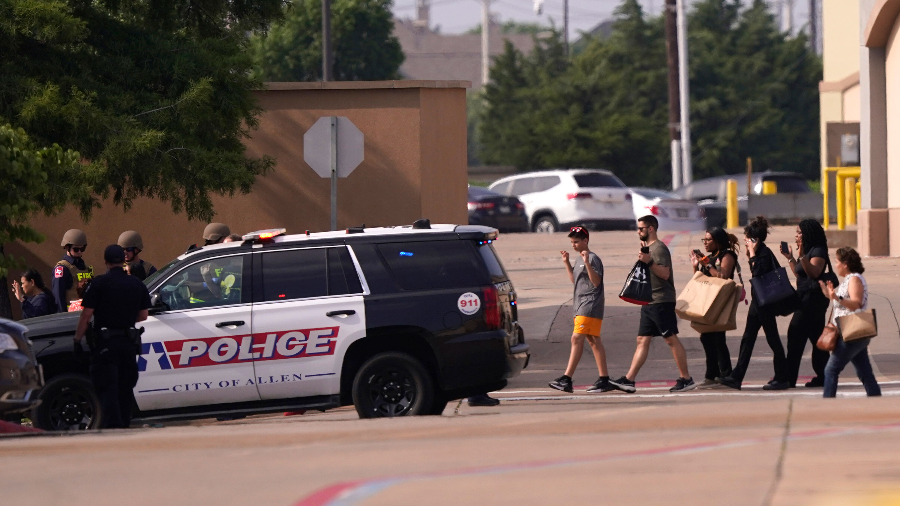 People raise their hands as they leave the shopping center after a shooting in Allen, Texas, May 6, 2023. /AP