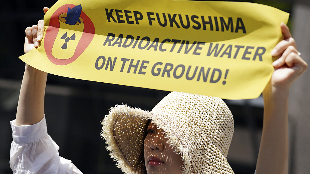 A protester holds a banner during a rally outside Tokyo Electric Power Company headquarters building in Tokyo, Japan, May 16, 2023. /CFP