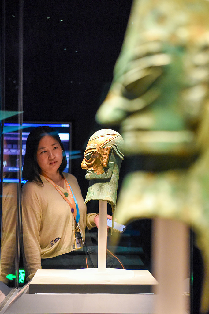 A visitor appreciates a bronze sculpture of a human head with a gold mask unearthed at the Sanxingdui Ruins site exhibited at the Anhui Museum. /CFP