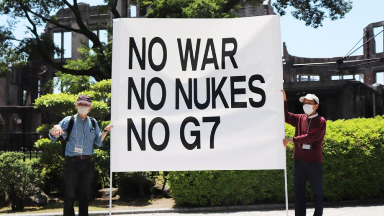 People hold a banner against the Group of Seven (G7) summit at the site of the atomic bombing near the Peace Memorial Park in Hiroshima, Japan, May 14, 2023. /Xinhua
