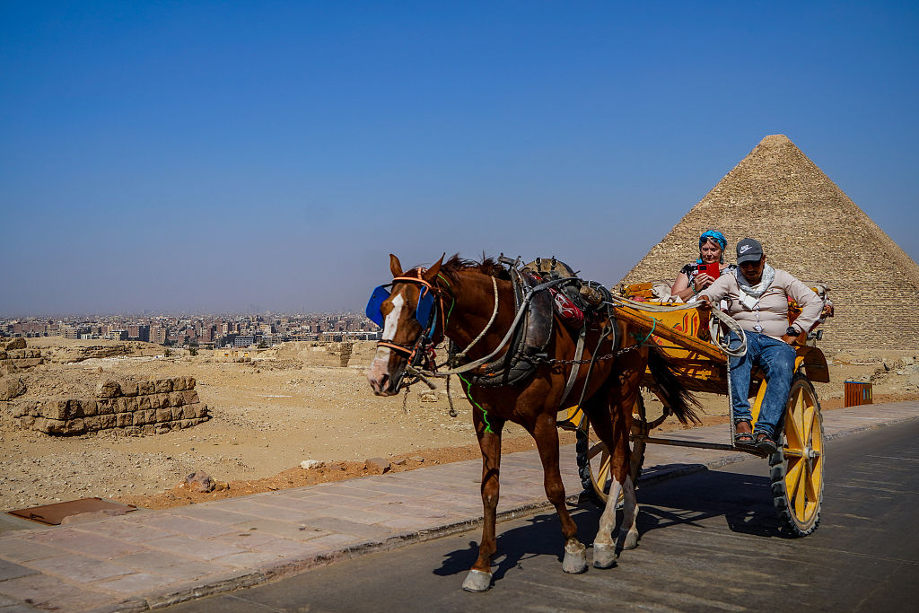 A tourist is seen riding a horse carriage against the backdrop of the Great Pyramid of Giza on April 15, 2023. /CFP