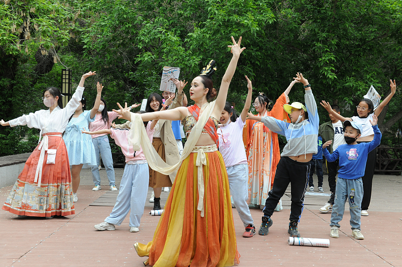 A performer dances with visitors in Urumqi, Xinjiang Uygur Autonomous Region. /CFP