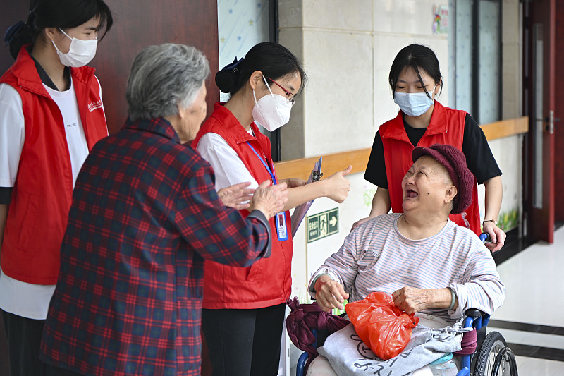 Staffs chat with an elderly person at a nursing home in Guangzhou City, southern China's Guangdong Province, April 12, 2023. /CFP