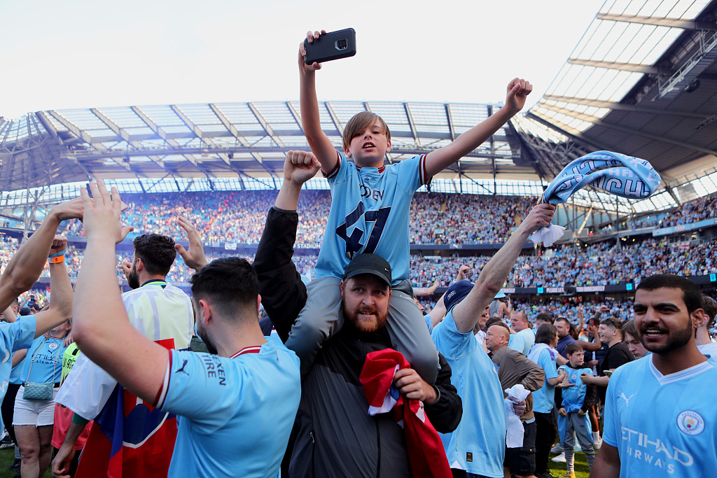 Manchester City fans celebrate being crowned Premier League champions on the pitch at Etihad Stadium in Manchester, England, May 21, 2023. /CFP