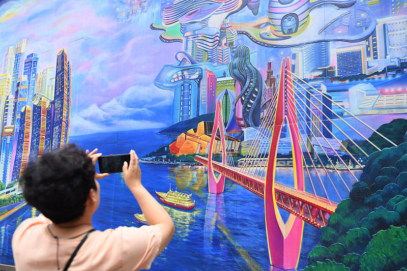 A resident takes photos of a giant three-dimensional mural in Chongqing on May 23, 2023. /CFP