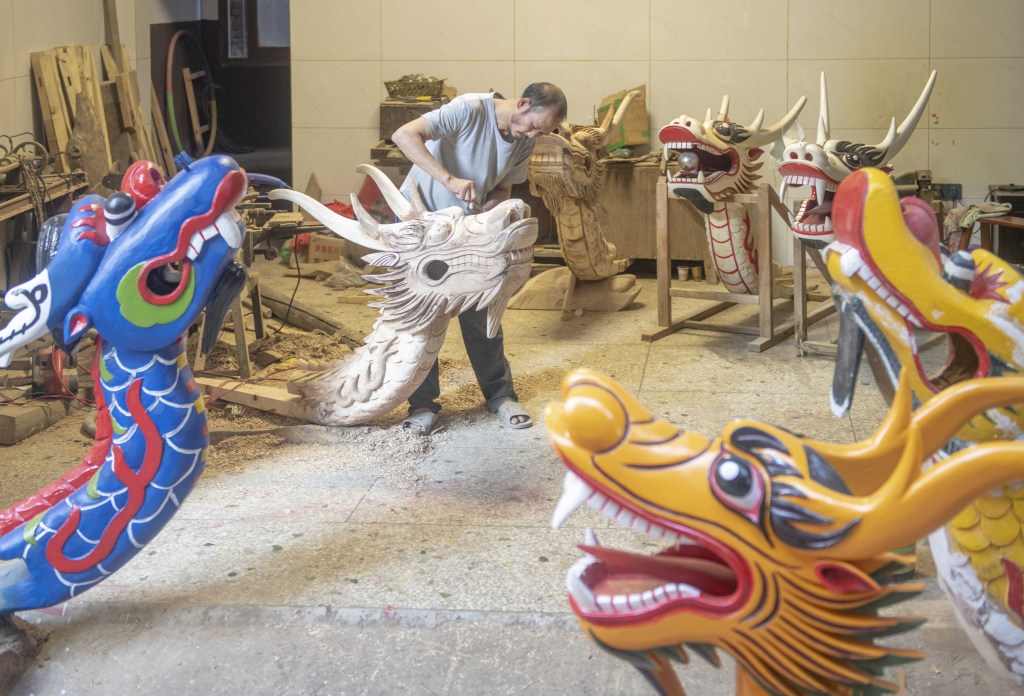 Photo taken on May 27, 2023 shows a craftsman from Yongzhou, Hunan Province, busy with making ornately carved dragon heads to welcome the upcoming Dragon Boat Festival. /CFP