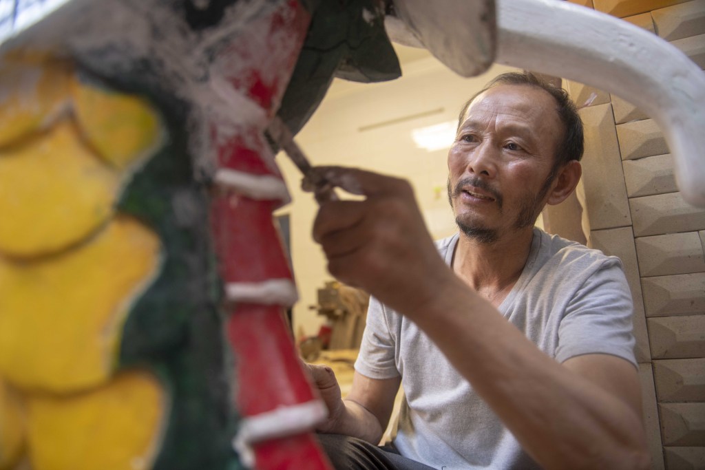 Photo taken on May 27, 2023 shows a craftsman from Yongzhou, Hunan Province, busy with making ornately carved dragon heads to welcome the upcoming Dragon Boat Festival. /CFP