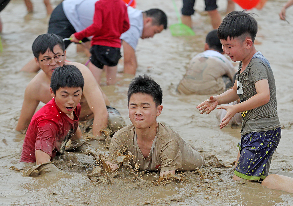 A group of boys try to catch fish in a muddy pond at a village in Hangzhou, east China's Zhejiang. /CFP