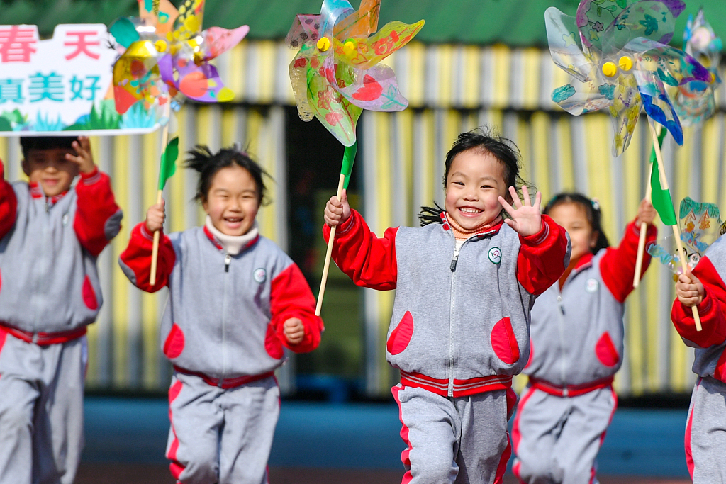 Children at a kindergarten happily run on a playground with colorful windmill toys in their hands in Si'an, east China's Zhejiang. /CFP