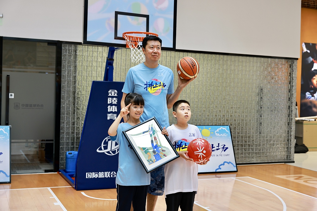Former Chinese national basketball team player Wang Zhizhi (C) poses for a photo with two Special Olympics athletes in the 