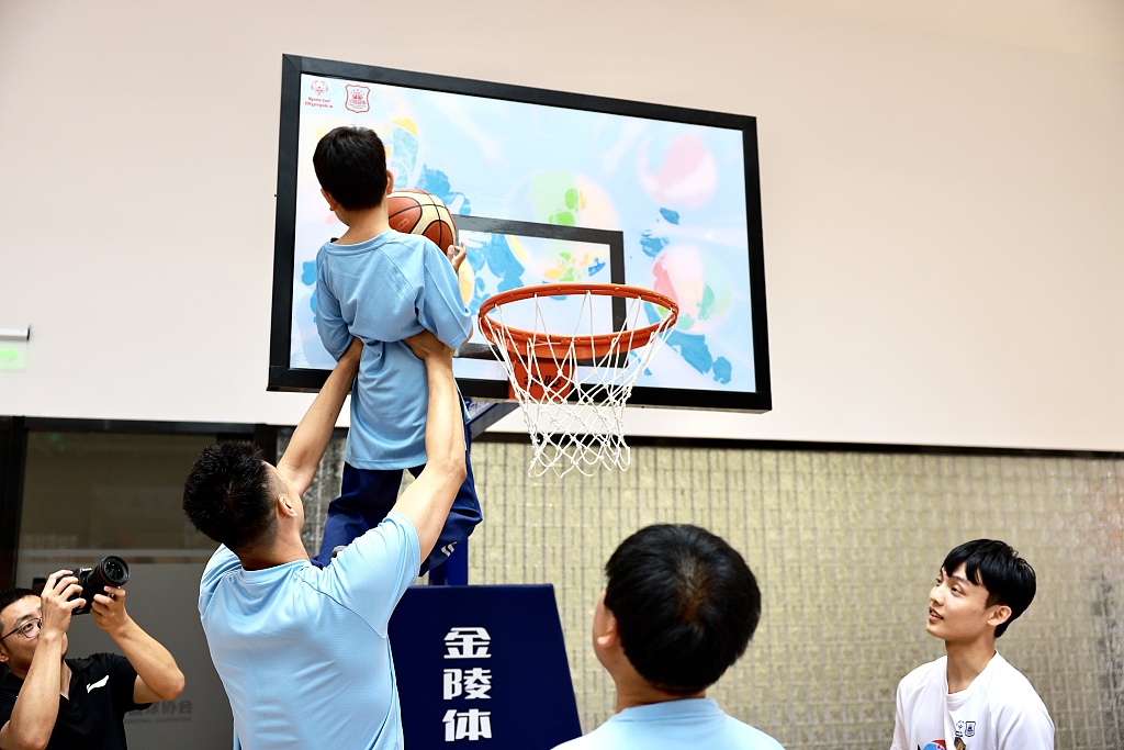 CBA player Zhai Xiaochuan helps a Special Olympics athlete dunk in the 