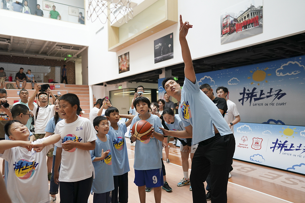 CBA player Zhai Xiaochuan (R) teaches a Special Olympics athlete how to shoot in the 