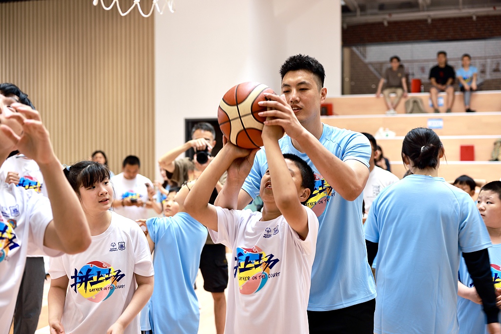 CBA player Zhai Xiaochuan (C) helps a Special Olympics athlete shoot in the 