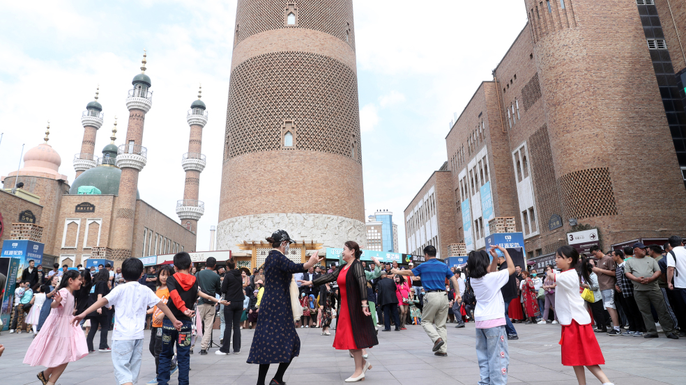 Adults and children dance on the square at the Xinjiang International Grand Bazaar in Urumqi, northwest China's Xinjiang Uygur Autonomous Region on June 1, 2023. /CFP