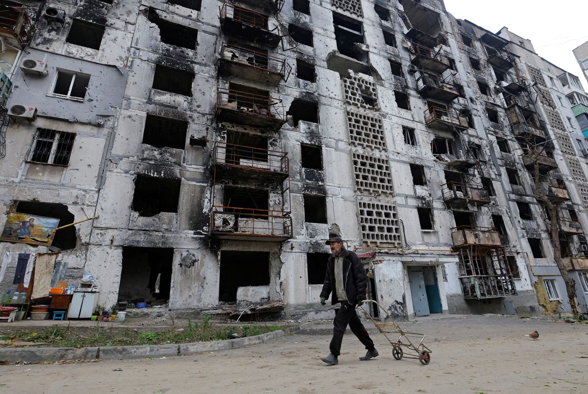 A man walks past an apartment building heavily damaged in the Russia-Ukraine conflict, in Mariupol, Ukraine, November 16, 2022. /Reuters
