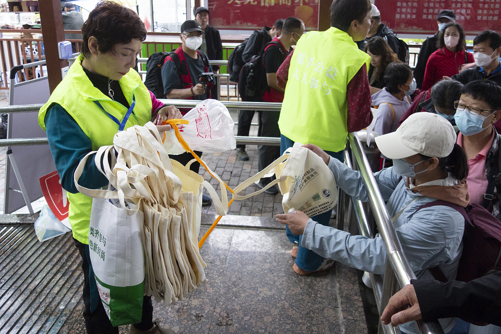 Volunteers offer tourists biodegradable bags in exchange for their plastic bags in Wenzhou, Zhejiang Province, May 7, 2023. /CFP