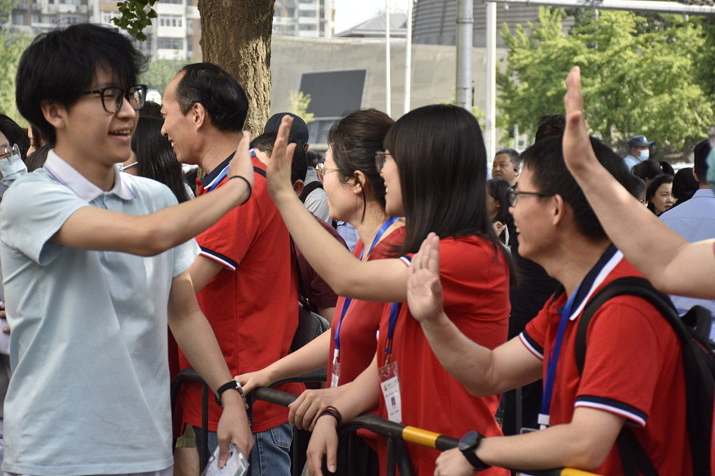 A teacher gives high fives to his students before they enter an examination room in Beijing, June 7, 2023. /CFP