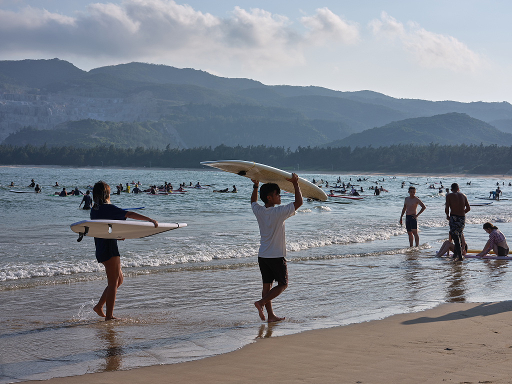Tourists surfing in Houhai Village, Sanya City, Hainan Island, south China. /VCG