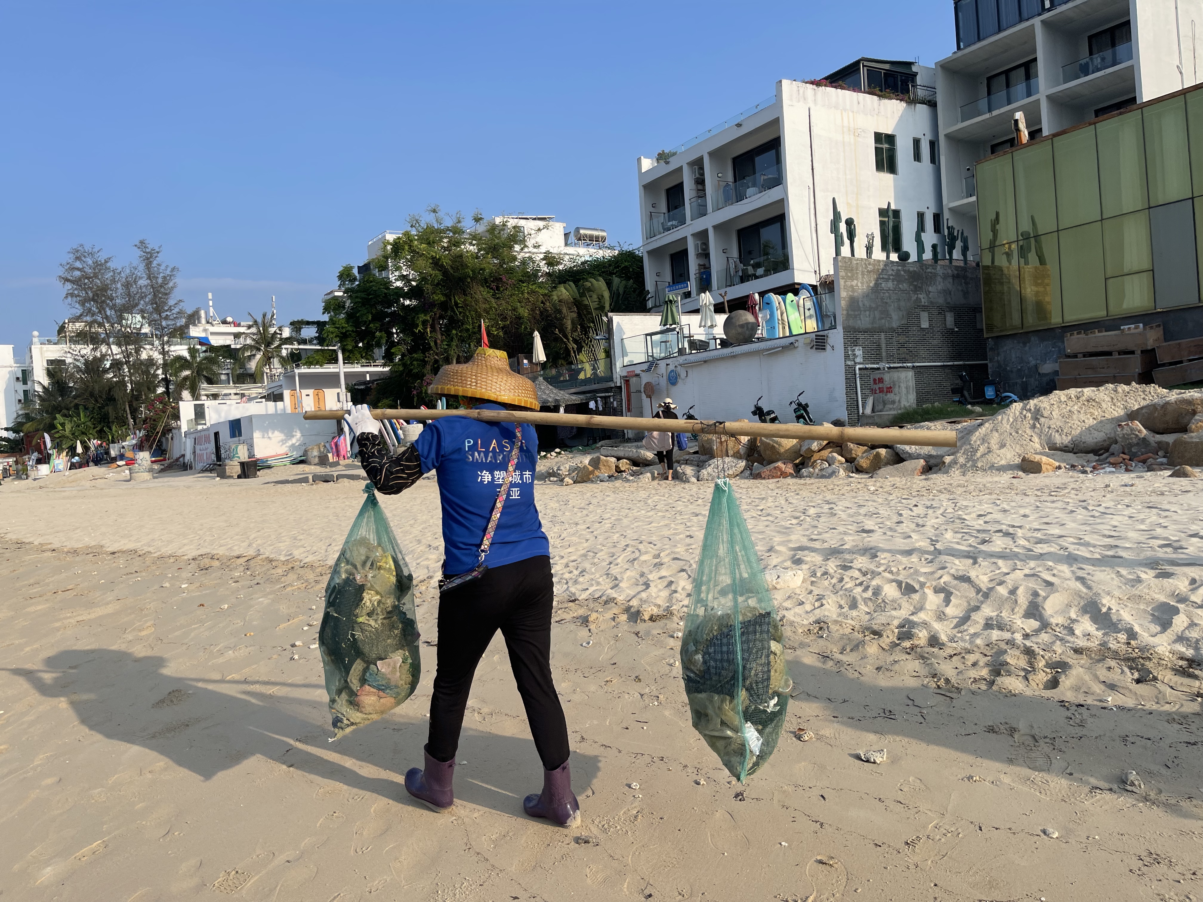 Volunteer carrying garbage on a bamboo pole on the beach of Houhai Village, Sanya City, Hainan Island, south China. /Blue Ribbon
