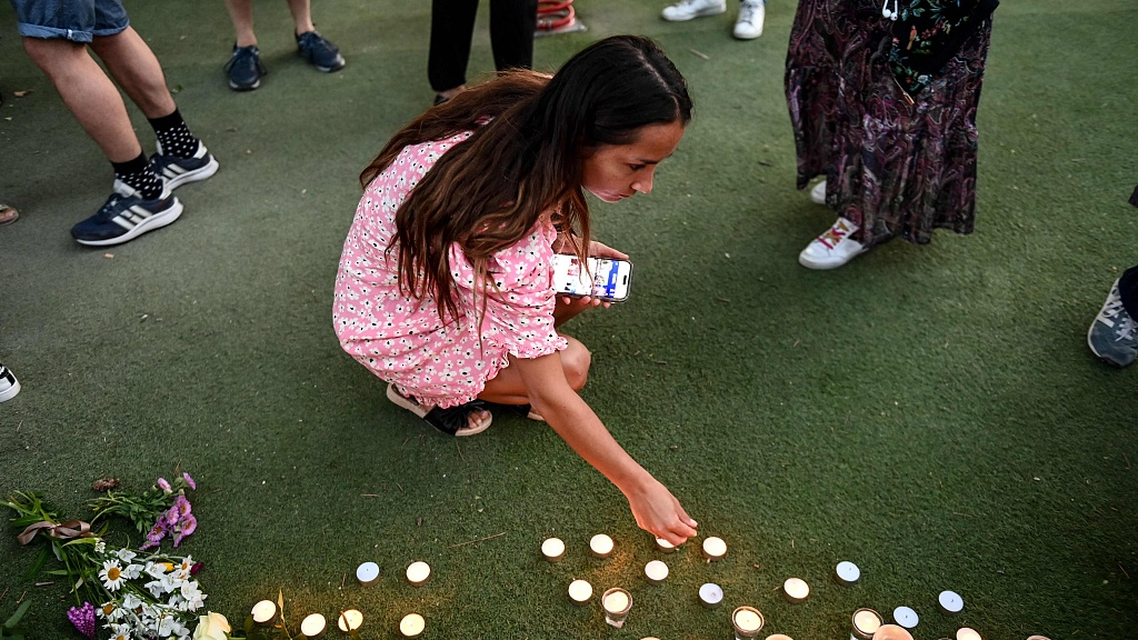 A woman lights candles at a playground in the 