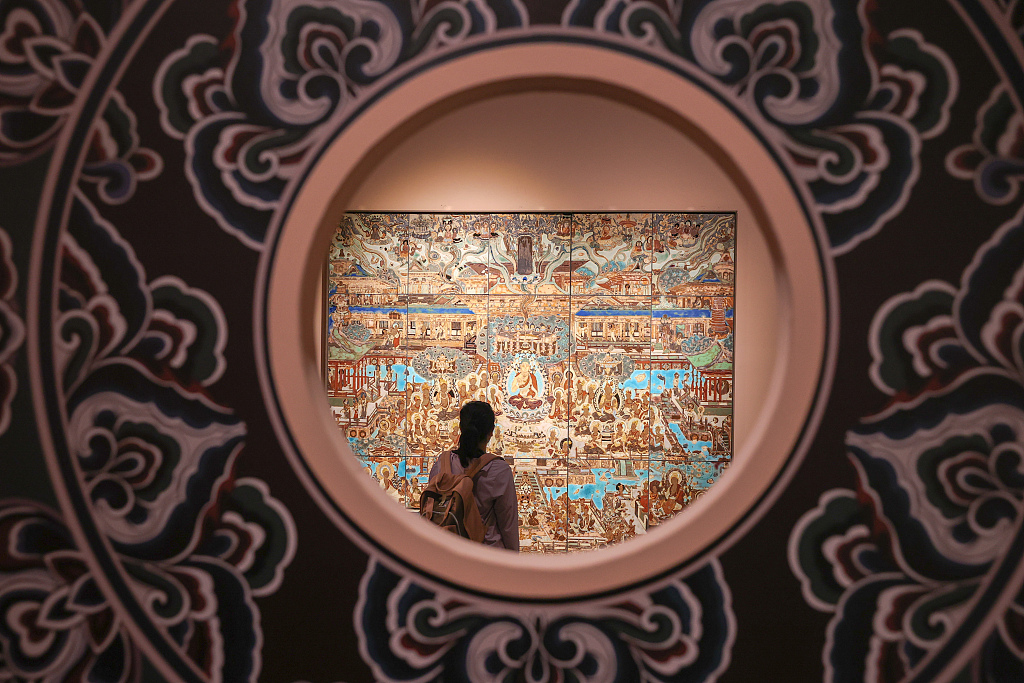 A visitor stands in front of a piece of porcelain painted with Dunhuang mural patterns at the Jiangxi Museum in Nanchang, Jiangxi, on June 9, 2023. /CFP