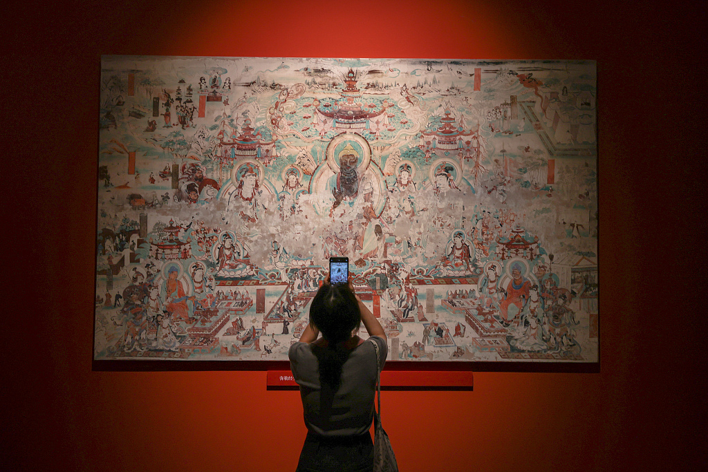 A visitor stands in front of a piece of porcelain painted with Dunhuang mural patterns at the Jiangxi Museum in Nanchang, Jiangxi, on June 9, 2023. /CFP