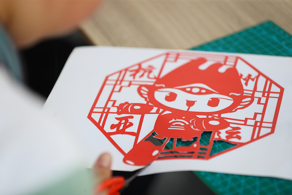 A student from a primary school in Huzhou, Zhejiang makes a paper-cutting of a mascot of the 19th Asian Games on June 9, 2023. /CFP