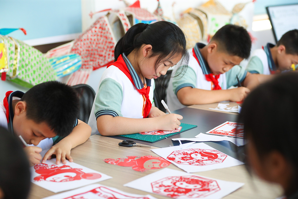 Students from a primary school in Huzhou, Zhejiang learn paper-cutting skills and produce a series of patterns involving the mascots of the 19th Asian Games on red paper on June 9, 2023. /CFP