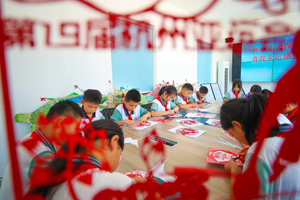 Students from a primary school in Huzhou, Zhejiang learn paper-cutting skills and produce a series of patterns involving the mascots of the 19th Asian Games on red paper on June 9, 2023. /CFP