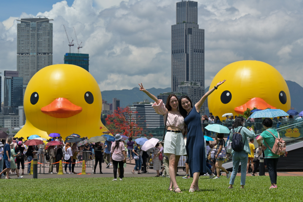 Visitors take photos with two giant rubber ducks floating in Hong Kong's Victoria Harbor on June 10, 2023. /CFP